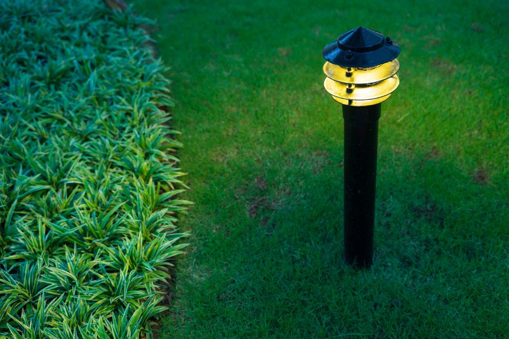 A well-lit path through grass, featuring a classic lamp post illuminating the walkway.