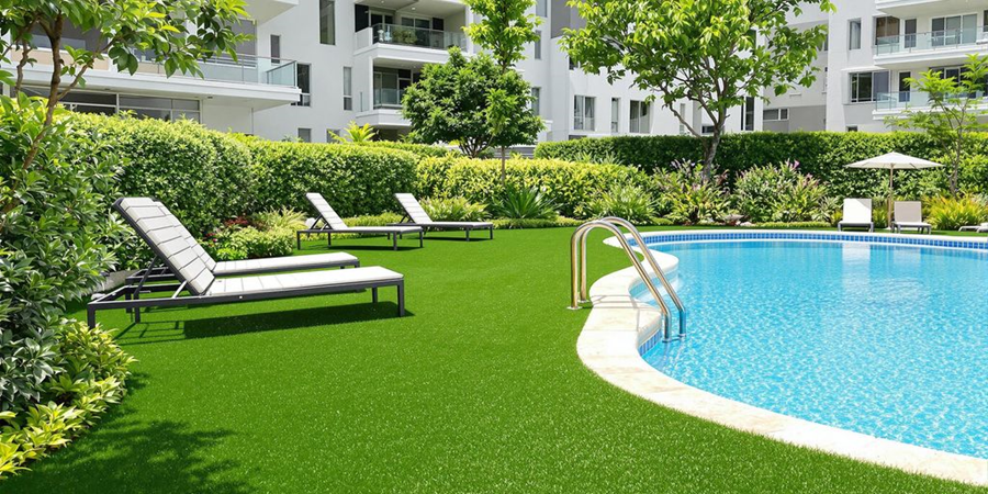 A pristine swimming pool framed by artificial grass, enhancing the landscape with a clean and stylish appearance.