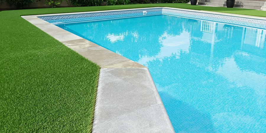 Artificial grass surrounds a swimming pool, creating a clean and sleek landscape for a modern outdoor space.